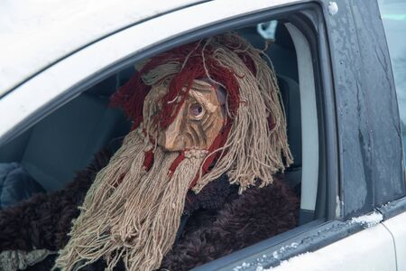 Russia. Tver region Village "White outside." January 7, 2020. Caroling in the village. National holidays and customs. A man in a scary mask sits behind the wheel of a car.のeditorial素材