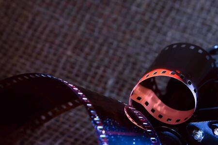 An old film reflects light in the dark. Film strip against a dark background, artistic lighting.の写真素材
