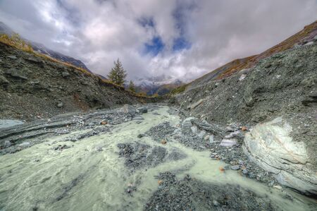 Mountain landscape. Rocks, stones, mountain river, blue sky, clouds. The mountains. covered with...