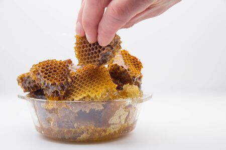 Natural honey lies in a glass plate. A man takes honey from a plate. Natural food.の写真素材
