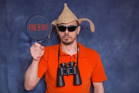 Funny man on a blue background. A man with glasses, with binoculars. Fool's day concept.