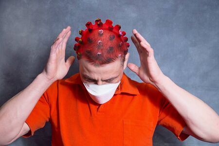 A man is in a panic over the spread of covid-19. A man is afraid of becoming infected with covid-19. The man in fear raised his hands to his head. A man thinks of a coronovirus. Concept of people fear of covid-19 infection.の写真素材