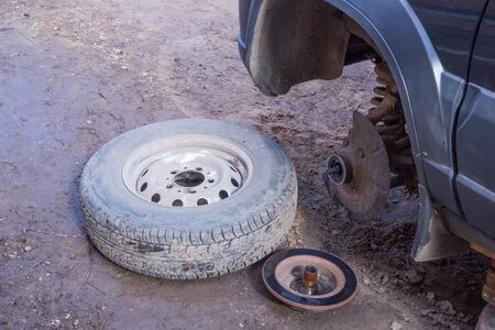 A broken wheel lies on the road. The car's wheel fell off. Front wheel drive car. Car repairA broken wheel lies next to the car. Breakdown on the road. Urgent car repair.の写真素材