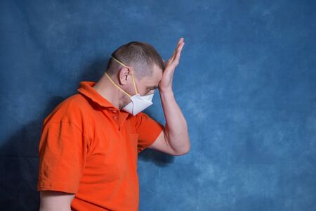 A man in a medical mask put his hand to his forehead. The concept of panic and fear of the COVID-19...