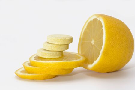 Yellow lemon cut into slices. Round vitamins lie on lemon slices. The concept of increasing immunity with vitamins.の写真素材