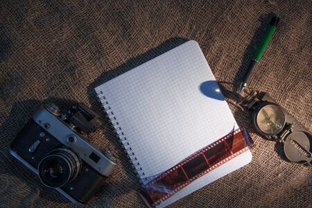 White sheet of paper. Fountain pen, kopmas, film camera lie on an old canvas. Travel concept.の写真素材