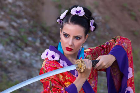 A woman in Chinese clothing holds a sword in her hands. Woman warrior with a sword.の写真素材