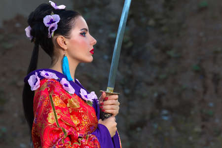 A woman in Chinese clothing holds a sword in her hands. Woman warrior with a sword.の写真素材