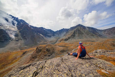 Young woman looks at mountains and clouds. Beautiful mountain landscape with a man. Travel and...