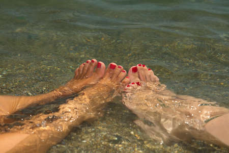 Women's feet in sea water. Sea vacation concept.