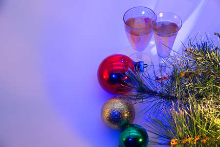 New Year's toys, spruce branches, glasses with a drink on a blue background. New Year holiday...