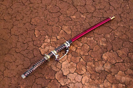 The Japanese sword lies on the cracked ground.