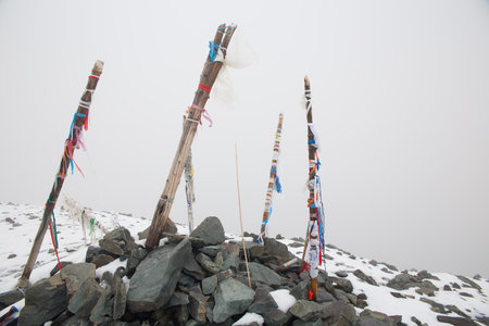 Mountain top, mountain pass marked by a pile of stones. Wooden poles with colored ribbons attached.の写真素材