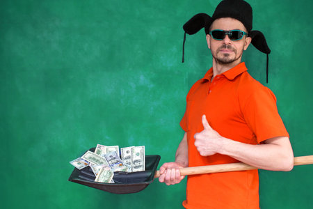 A charismatic man holds dollar bills on a shovel.の写真素材