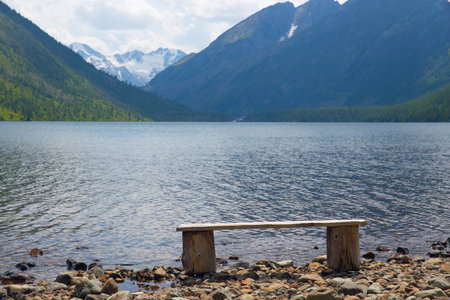 The bench stands on the shore of a mountain lake. Outdoor recreation concept.の写真素材