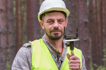 Forest worker works in the forest with a forestry compass. Real people work in forestry.の写真素材
