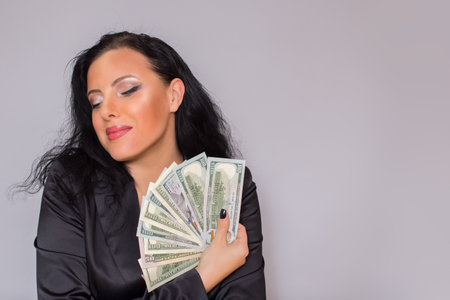 A European woman, a brunette, holds dollar bills in her hands.の写真素材