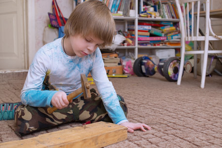 A European boy learns to hammer nails in. A photo with a shallow depth of field.の写真素材