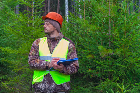 Forest engineer works in the forest. An ecologist oversees the development of a young forest. Growing forests in the timber industry.の写真素材