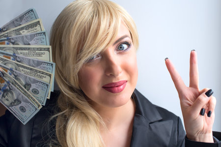 A blonde woman holds dollar bills in her hands.の写真素材