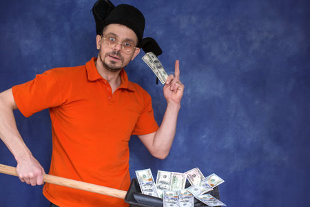 Charismatic man holding dollars on a shovel. The concept of big profits in business.の写真素材
