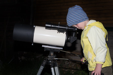 A child is watching the stars through a telescope.