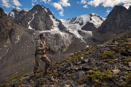 Male traveler on the background of high snow-capped mountains.
