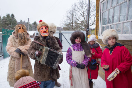 Russia. Tver region. The village "White outside". January 7, 2020 Caroling in the village. National holidays and customs. People in suits and masks stand in the courtyard of a village house. A man plays the acardion.のeditorial素材
