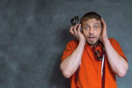 a European man with a film camera in his hands. Photographer with an analog camera and photographic film.の写真素材