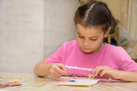 Children paint with paints and colored sand in a village house. Children are busy with creativity.の写真素材