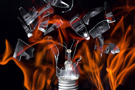 Flames on a black background. Broken incandescent lamp and glass shards.