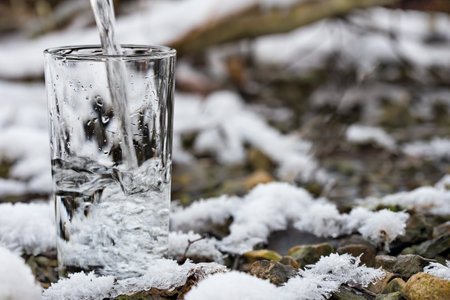 Pure water is poured into a glass beaker. Snow lies on the ground.の写真素材