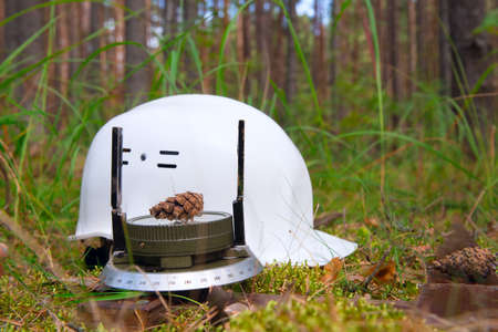 The forest compass and hard hat lie on the ground in the forest. The concept of working in the...