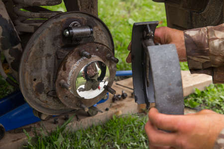 A European man is repairing a car. A man repairs the wheel hub of a car.の写真素材