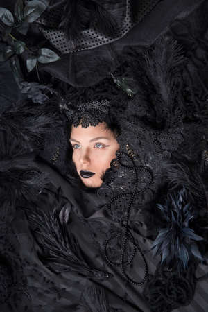 The face of a young woman against a background of black fabric.