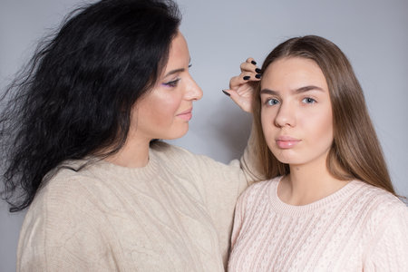 A woman with black hair next to a young girl. Mom is next to her daughter.