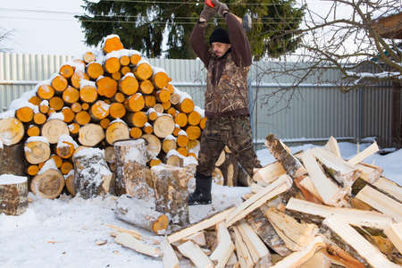 A man chops wood in winter, swings an ax. Stripes from flying snow across the entire image area.の写真素材