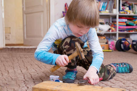 The boy learns to work with construction tools. A child hammers in a nail.の写真素材