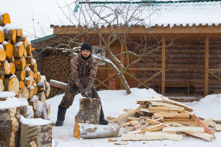 A man chops wood for a bath. A man stands with a cleaver in his hands.の写真素材