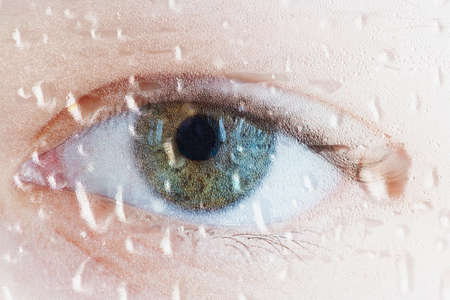 Human eye through wet glass. Water drops, sadness and sadness concept. Focusing on water droplets.