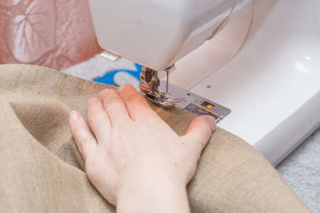 Sewing machine mechanism. Human hand in the frame. Close-up photo. Shallow depth of field.