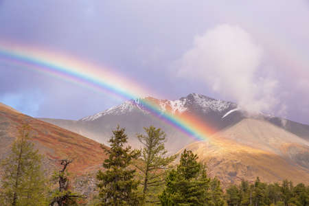 Beautiful rainbow in the mountains. Rain clouds.の写真素材