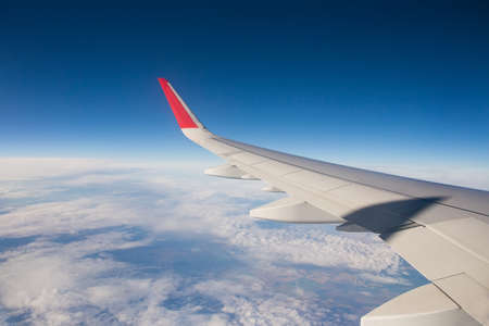 Airplane wing above white clouds. Selective focusing on the wing. The shadow on the wing of an...