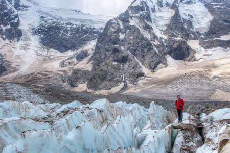 August 8, 2021. Russia. Republic of Kabardino-Balkaria. woman in a red jacket stands on the glacier. Mountains in the background.のeditorial素材