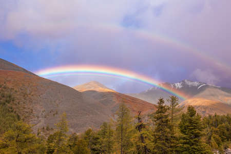 Beautiful rainbow in the mountains. Rain clouds.の写真素材