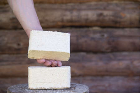 Fuel briquettes from sawdust against the background of a log wall.の写真素材