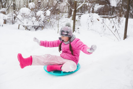 The girl goes for a drive in the winter from a snow slide. Soft focus. Shooting a subject in motion.の写真素材