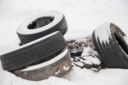 Old car tires lie on white snow.の写真素材