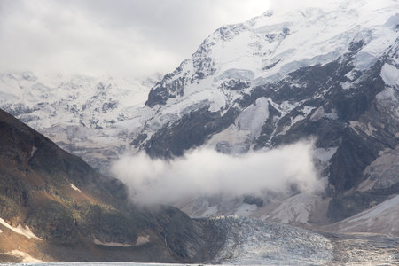 A cloud hangs over a glacier in a mountain valley.
