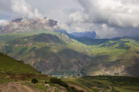 Top view of the mountain valley and the mountain village. Clouds and cumulus clouds over the...
